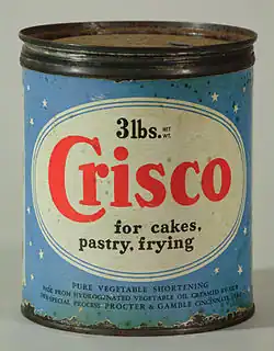 Boîte de Crisco d'époque : Boîte cylindrique en métal avec une étiquette en papier bleu à l'extérieur ; l'étiquette en papier identifie le produit, le poids et le fabricant, comme suit : "3lbs. NET WT / Crisco / for cakes, / pastry, frying / PURE VEG