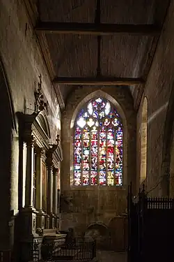 Photographie montrant un bras de transept d'église, couvert d'un lambris et éclairé par un vitrail.