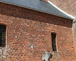 Sur le mur sud de la nef est écrite en briques vernissées la date de 1690 avec un curieux dessin en briques pouvant représenter un être humain.