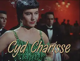 Image du film où Cyd Charisse, une femme portant une robe verte et des cheveux noirs courts, sourit. Sur l'image est incrusté son nom en lettres dorées.
