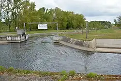 Début de la rivière artificielle avec un panneau suspendu au-dessus du parcours