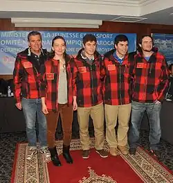 5 personnes dont une femme en veste de ski à carreaux rouges et noirs, pantalon de ville