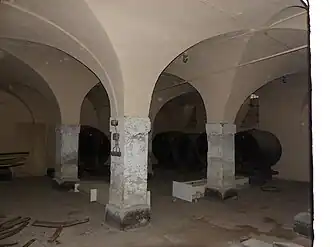 Photographie d'une cave ancienne dont les voûtes s'appuyent sur des piliers de maçonneries massifs.