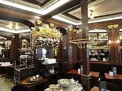 La brasserie avec ses murs en acajou, ses lampes tulipe et ses chapelières en cuivre.