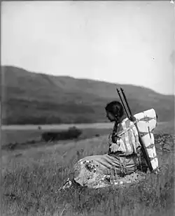 Daisy Norris, pikunie, portant un porte-bébé sur planche avec un nourrisson dedans, Parc national de Glacier, Montana