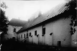 Bâtiments anciens en pierre, noir et blanc, lumière brumeuse, ambiance mystérieuse.