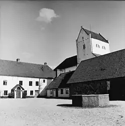 Vue monochrome d'un bâtiment ancien avec tour, textures mises en valeur, ambiance paisible.
