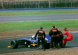 Vue d'une monoplace violette en piste, tirée par quatre hommes