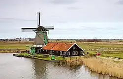 Un moulin au bord d'un point d'eau.