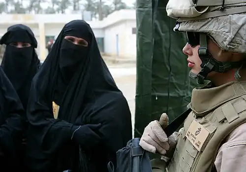 Femmes portant un niqab et marine américain gardant l'entrée d'une clinique médicale à Saqlawiyah en Irak (2008).