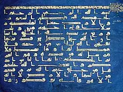 Photographie d'un feuillet du Coran bleu, conservé au musée national du Bardo. Écrit en coufique doré sur du vélin teint à l'indigo, il provenait à l'origine de la bibliothèque de la Grande Mosquée de Kairouan.
