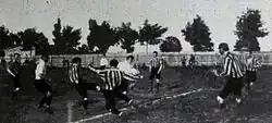 Photographie en noir et blanc d'une scène d'un match de football.