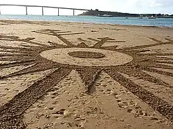 Dessin sur le sable de la plage représentant un flocon de neige.