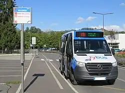 Photographie en couleurs d’un minibus bleu, blanc et noir stationné à un arrêt de bus. Il circule sur la ligne 1, alors la plus fréquentée du réseau.