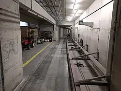 Le tunnel, avec à gauche la zone technique permettant de réceptionner une rame grutée depuis l'extérieur et, à droite : le système de guidage et le câble de traction (en bas), le retour du câble (en haut) et la caténaire au plafond. Les traces de passage des coussins d'air sont visibles.