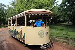 Véhicule léger routier de transport collectif. Il est non vitré et sur son flanc sont peints des représentations des principaux sites du parc.