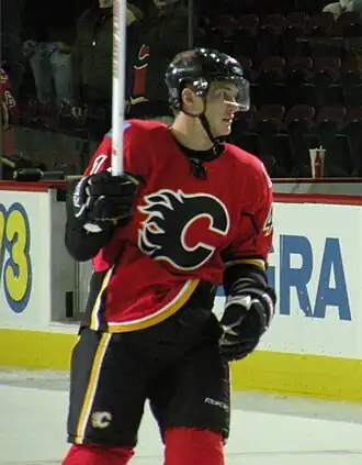 Photographie de Boyd en tenue de hockey qui regarde à gauche et lève son bâton