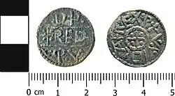 Photo des deux faces d'une pièce de monnaie. Une face porte des lettres gravées sur trois lignes, l'autre porte une inscription circulaire autour d'un motif central en croix