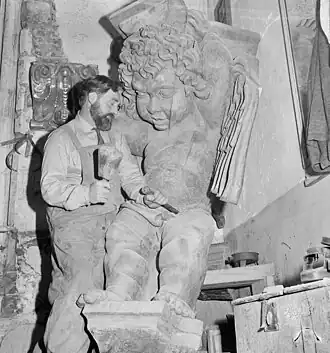 Le sculpteur néerlandais Maarten Mooij&nbsp;(nl), en 1964, opérant un travail de finition à l'aide d'un maillet, sur un ange en bois destiné à la Nouvelle église d'Amsterdam.