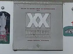 Photographie montrant la plaque du label « Patrimoine du XXe siècle » sur l'église du Sacré-Cœur de Bonnecousse