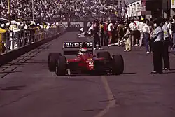 Photo de la Dallara 191 rouge, vue de face, de Pirro, dans la voie des stands du Grand Prix des États-Unis