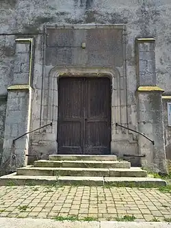 Entrée de l'église. Le style différent de celui du bâtiment principal fait penser au réemploi d'une porte provenant d'un édifice plus ancien