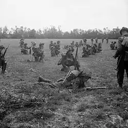 Photo présentant des fantassins britanniques arme au poing, dans un champ, attendant le signal pour lancer l'attaque