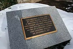 Photo agrandie d'une plaque comportant des inscriptions couleur or sur fond noir avec un large cadre gris en pierre.