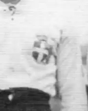 Photographie d'un buste d'un homme portant un maillot blanc avec un emblème dessus