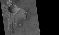 Un cratère à piédestal (HiRISE), Quadrangle de Casius. L'éjecta est asymétrique autour du cratère parce que l'astéroïde a percuté le sol avec un angle faible, venant du nord est.