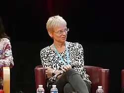 une femme cheveux blancs coupés cours, des lunettes, sur scène