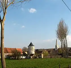 L'ancienne ferme fortifiée en pierre calcaire blanche et l'église.