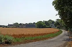 Photographie en couleurs d'un hameau traversé par une route.