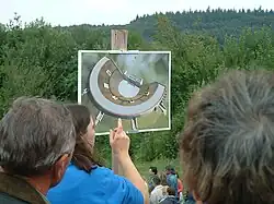 Présentation d'une reconstitution d'un théâtre antique devant un paysage de campagne