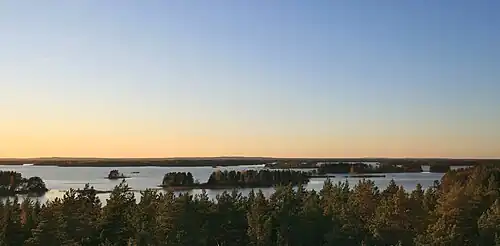 Coucher de soleil sur un grand lac avec des îlots boisés.