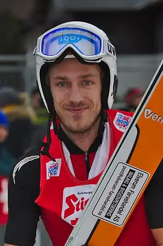 Le portrait d'un homme avec un casque et tenant des skis à la main.