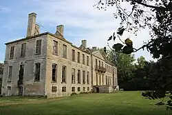 Vue d'un château ayant perdu son toit entouré d'une pelouse et d'arbres