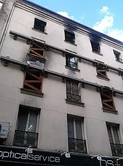 Vue du premier au 4e étage d'un immeuble, certaines fenêtres ont des traces noires de suie sur le dessus, d'autres ont des tasseaux ou sont murées.