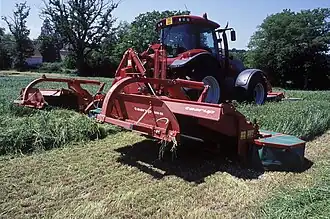 Ensemble faucheur-conditionneur à trois corps à disques mu par un tracteur d'environ 200 ch