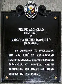 Plaque rectangulaire noir portant un texte blanc en tagalog sur onze lignes.