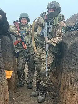 Photo couleur de deux militaires dans une tranchée.
