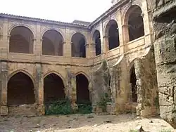 Photographie couleur d'un cloître monastique à deux niveaux.
