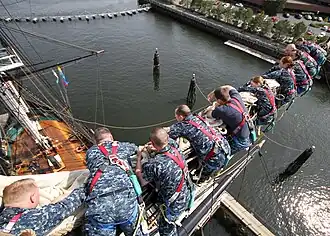 Les gabiers se déplacent sur un marchepied (sous la vergue pour se déplacer le long de la vergue (ici les cadets de l'US Navy sur l'USS&nbsp;Constitution).