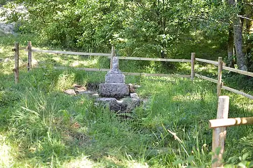 Vue générale du site de la fontaine, avec la barrière de bois protégeant le monument.