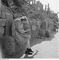 Femme lisant, assise sur le rebord d'un mur en ruine.