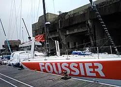 Voilier orange et blanc, vu de trois quarts avant.