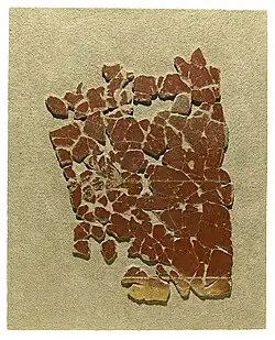 Fragments d'enduit peint, en majorité rouge mais figurant une bande jaune en partie basse.