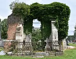 Vestiges du bas-côté sud de l'ancienne église : deux contreforts en pierre, un mur en brique et une baie.
