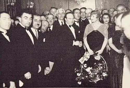 Photographie en noir et blanc d'une vingtaine de personnes posant devant un train de passagers.