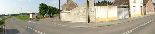 Panorama réalisé à Fresnes-sur-Escaut montrant la rue et les habitations. Une petite borne en béton apparaît le long d'un mur, il s'agit d'une tête de puits non matérialisée indiquant que le puits Jeanne Colard no&nbsp;1, creusé en 1718 et abandonné en 1721, se situe quelques mètres derrière.